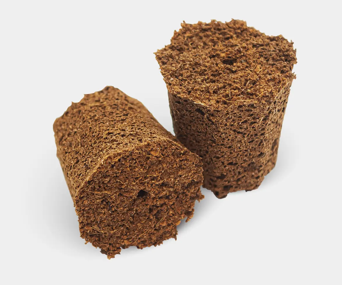 Two pieces of dark brown, crumbly compressed soil or organic matter, shown on a white background.