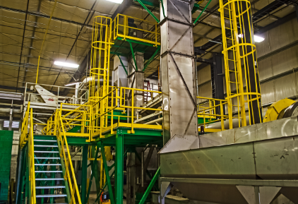 Interior of a fertilizer production facility with metal machinery and yellow safety railings.