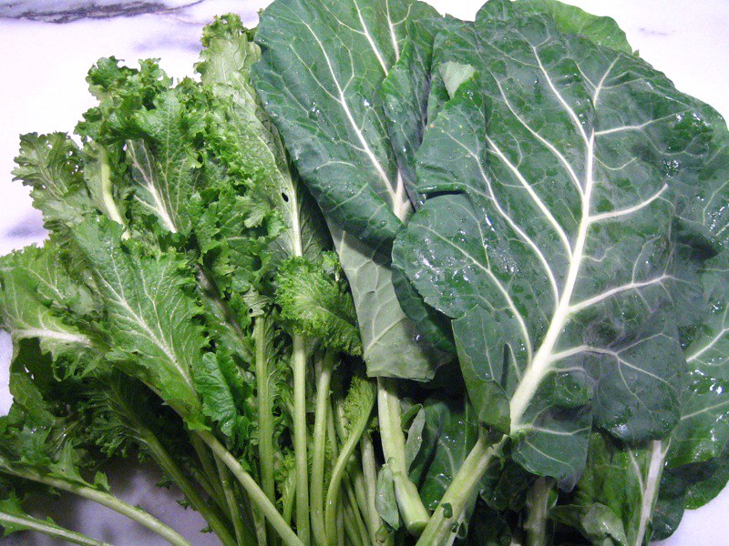Fresh collard greens and leafy greens spread out on a countertop.