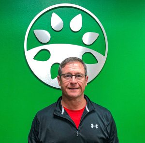 Florikan Senior Account Manager Kevin Branch standing in front of a bright green wall with the Florikan logo on it.