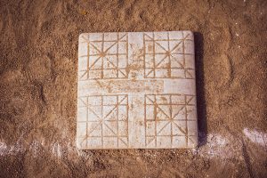 A square marble board with engraved geometric patterns sits on sandy ground, possibly used for a traditional game.