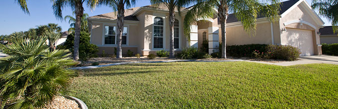 Well-maintained Florida home with green lawn and palm trees in front yard.