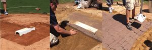 Three images show steps of installing a drainage system under a brick pathway: a drain is placed, bricks are laid on sand, and sand is swept over the finished path. Only peoples legs and hands are visible.