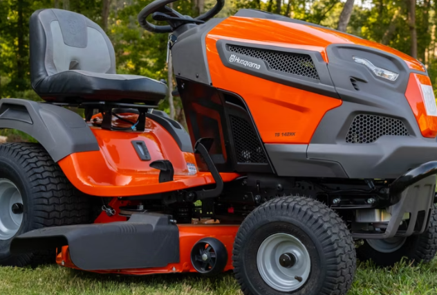 Orange riding lawn mower parked on grass in a yard.