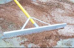 Landscape rake smoothing and leveling a baseball infield surface after soil treatment.