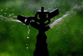 Garden sprinkler spraying water across a grassy lawn.