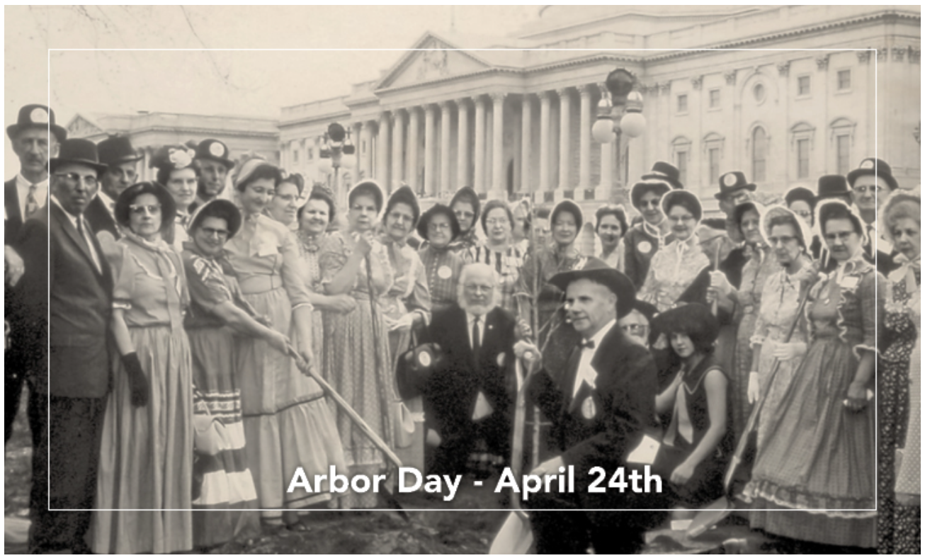 A large group of people in vintage clothing gather outdoors, some holding shovels, in front of a grand building. Text reads: Arbor Day - April 24th..