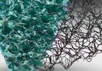 Close-up of two textured materials: a green, porous sponge-like surface on the left, and a black, tangled mesh structure on the right.