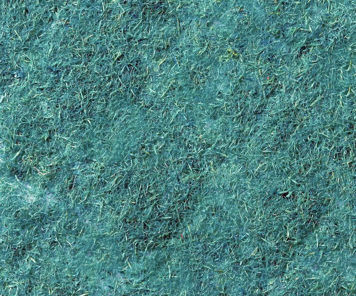 Close-up texture of green hydroseed mulch with visible shredded fibers and small organic fragments forming a dense ground cover.
