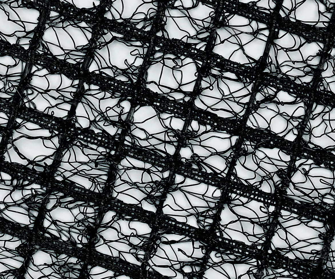 Close-up of black synthetic turf reinforcement mesh with an irregular web-like pattern forming a grid structure.