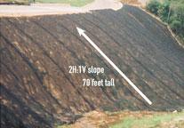Steep, grassy embankment with a white arrow labeled 2H:1V slope, 70 feet tall, illustrating the height and incline of the slope.