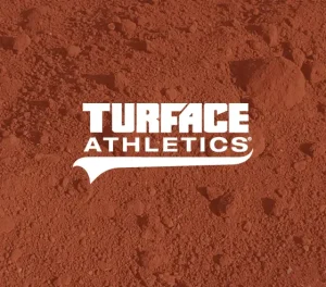 Close-up of red clay or crushed brick surface with white text reading “TURFACE ATHLETICS.”