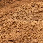 A close-up view of a large pile of loose, brown soil or mulch, with a rough and textured surface.