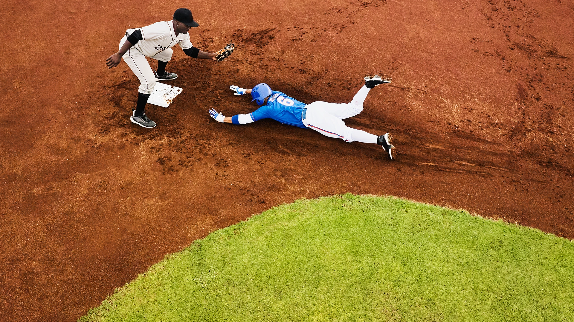 Baseball player sliding into second base.