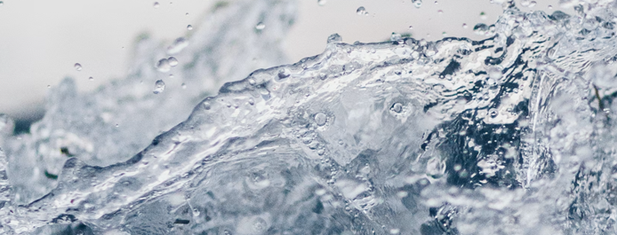 Close-up of splashing water with droplets frozen in motion against a light background.