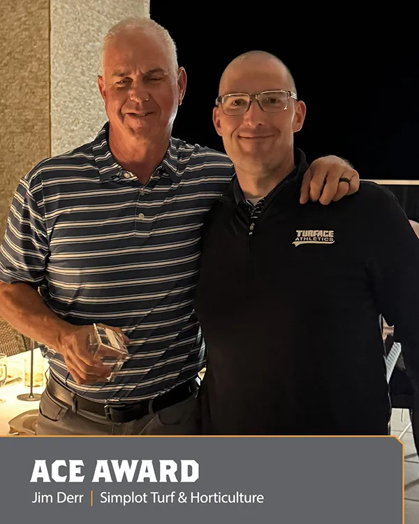 Two men stand together smiling, one holding a glass award. Both are wearing glasses and polos. The text at the bottom reads: ACE AWARD. Jim Derr | Simplot Turf & Horticulture..