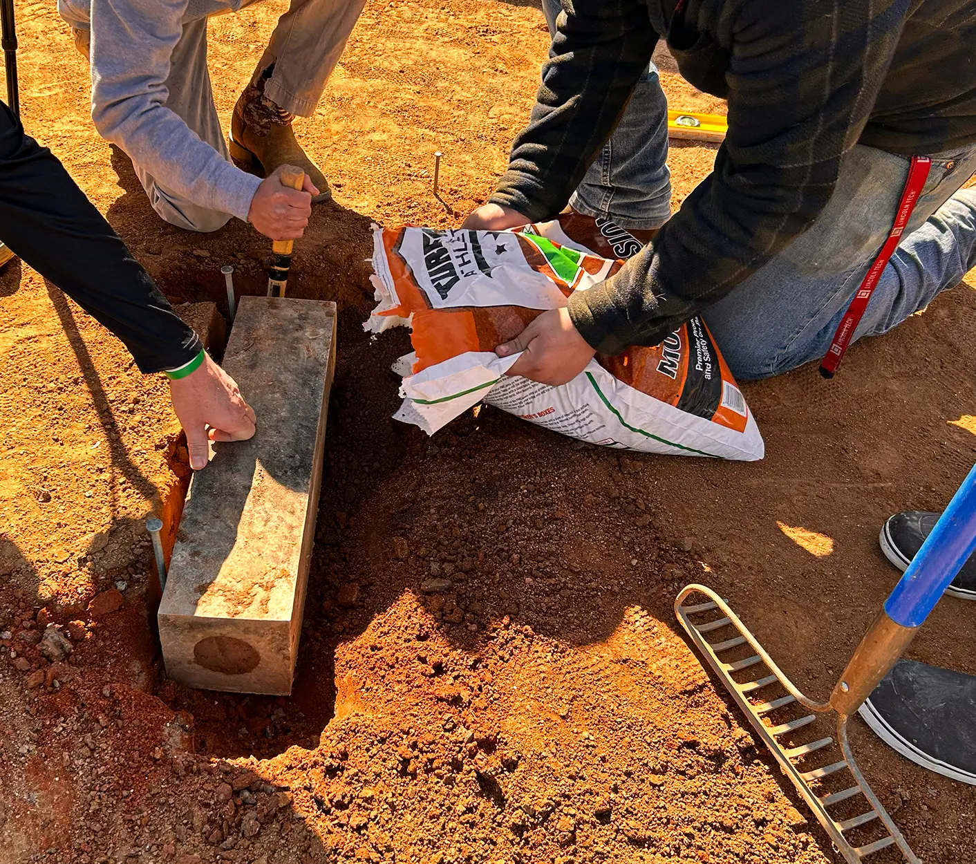 Three people using turface products to install a plate on the pitchers mound.