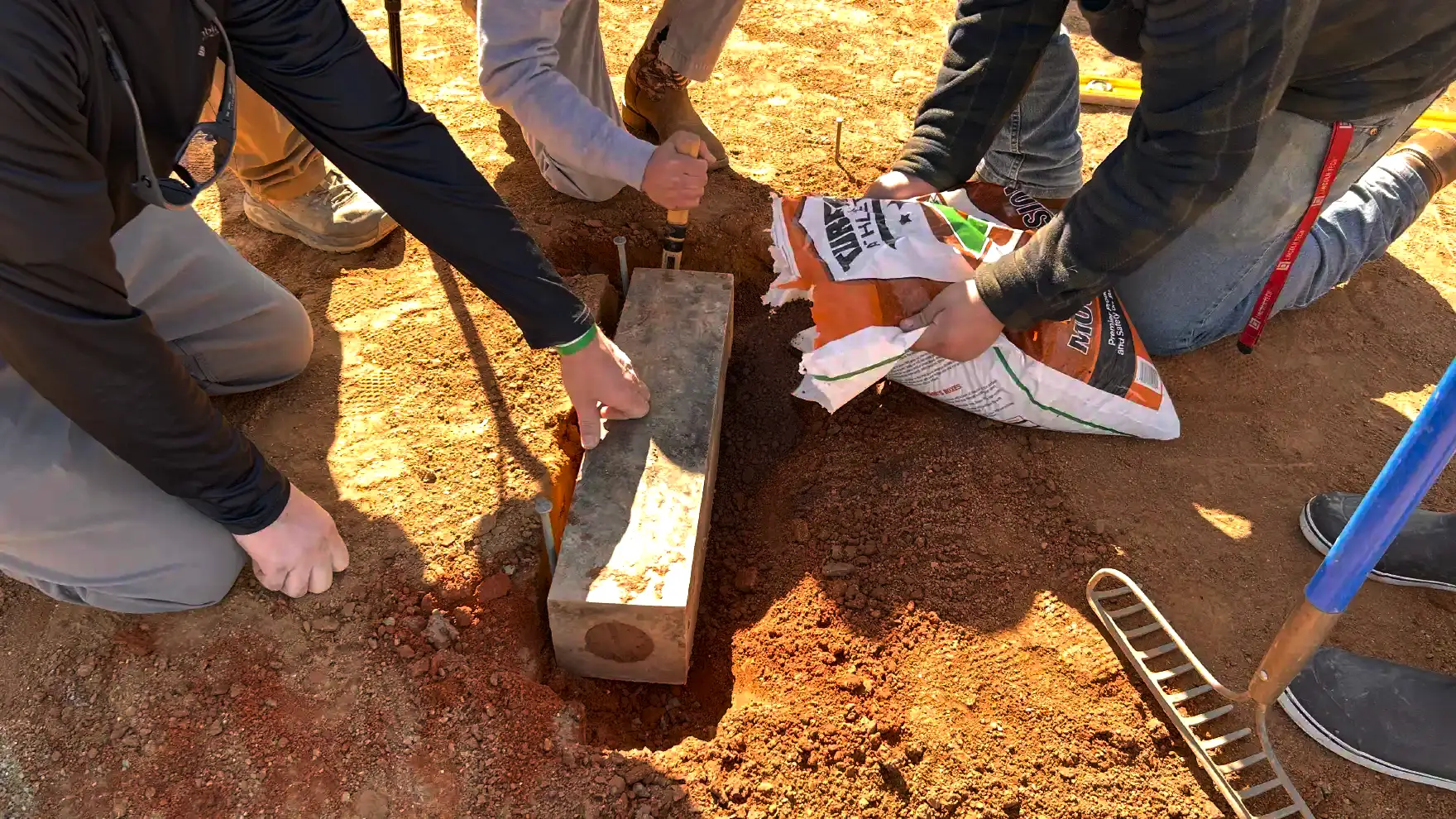 A group of people setting a pitcher's mount on a baseball field